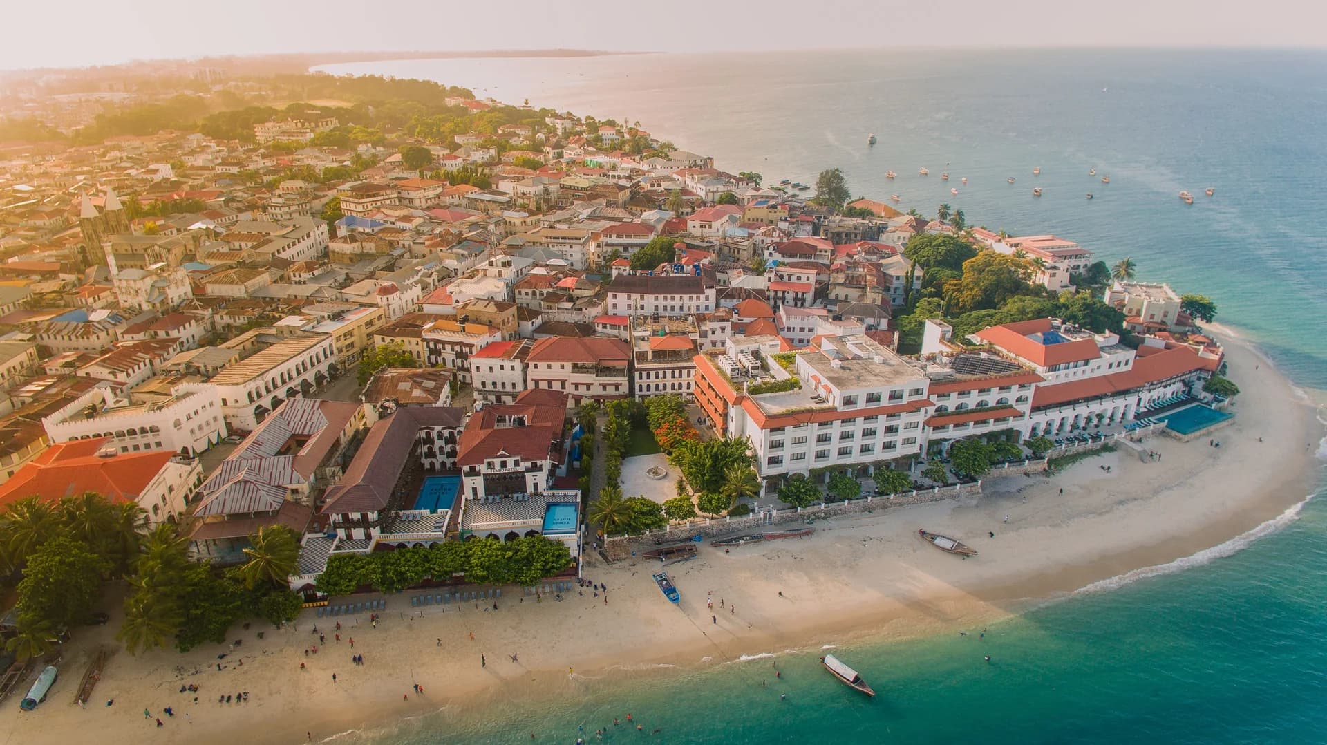 Aerial view of a historic seafront town with a sandy beach and moored boats
